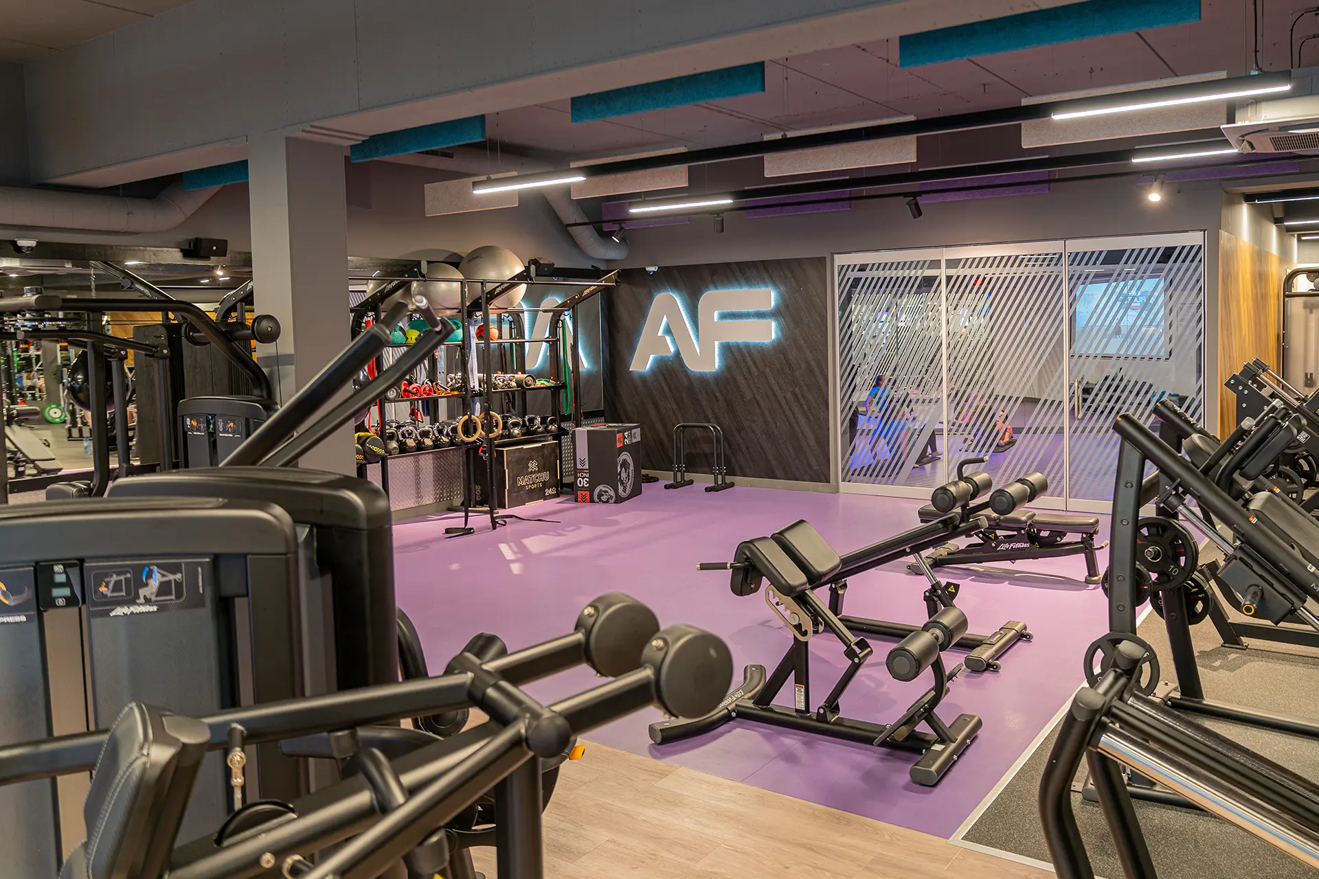 Bedrijfsfotografie van een moderne sportschool met paarse vloer en krachtapparatuur
